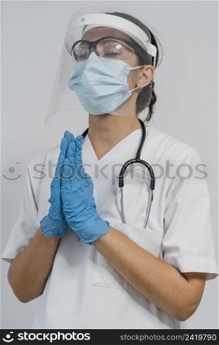 female doctor with medical mask face shield praying