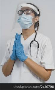 female doctor with medical mask face shield praying