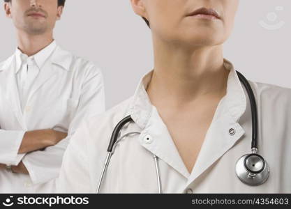 Female doctor with stethoscope around her neck and a mid adult man standing in the background