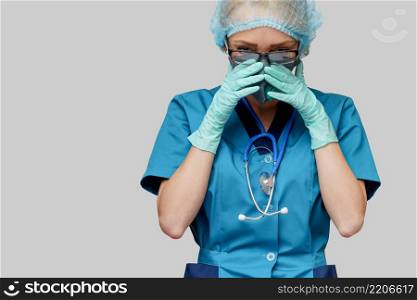 female doctor with stethoscope wearing protective mask and latex gloves over light grey background.. female doctor with stethoscope wearing protective mask and latex gloves over light grey background