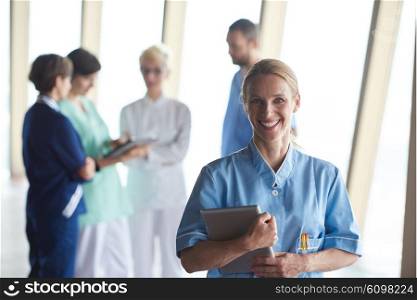female doctor with tablet computer standing in front of team in background, group of medical staff at hospital