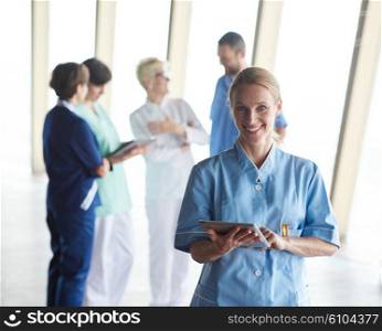 female doctor with tablet computer standing in front of team in background, group of medical staff at hospital