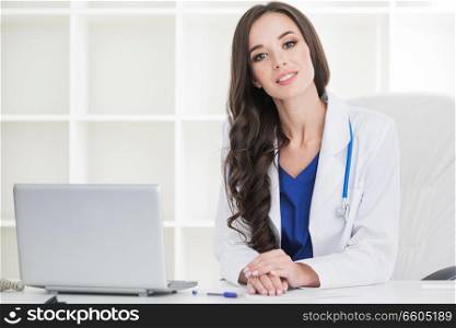 Female doctor working at office desk and smiling at camera , office interior on background. Female doctor working at office desk