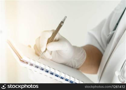 female doctor writing medical information in notebook at hospital