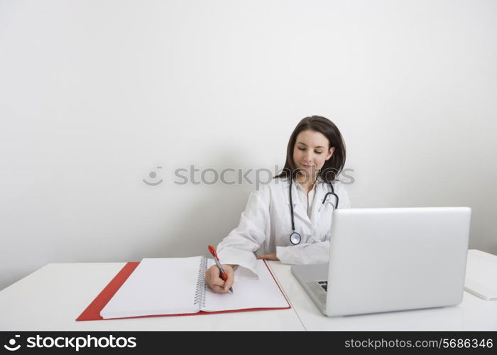 Female doctor writing on binder at desk in clinic