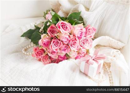 Female dress and jewellery with romantic roses bouquet and gift box on chair with copy space. Female accessories on white