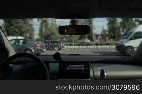 Female driver looking for empty space in open parking area near shopping mall on sunny summer day. View from inside of auto. Woman parking her car into the parking lot.