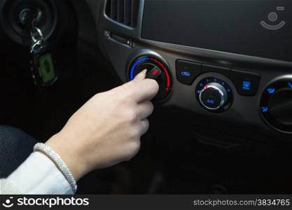 Female driver turning car air conditioner knob