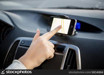 Female driver using touchscreen smartphone with GPS navigation