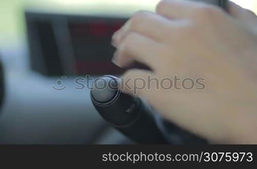 Female driver using turn signal switch while driving car. Focus on turn signal light on dashbord