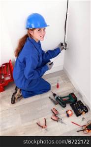 Female electrician fixing a wall socket