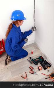 Female electrician installing a wall socket