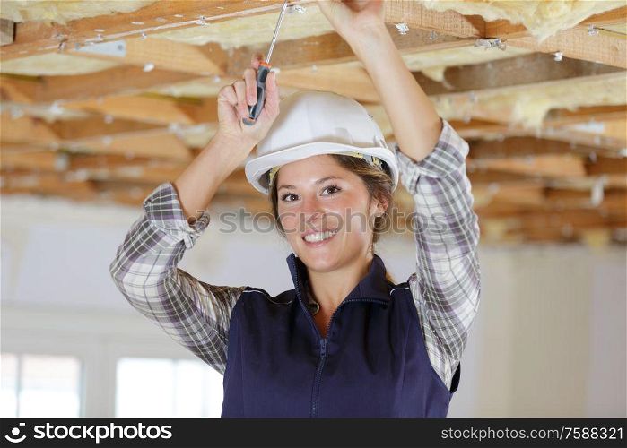 female electrician installing lights in ceiling