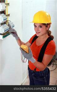 Female electrician taking reading form fuse box