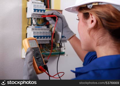 Female electrician taking reading from fuse box