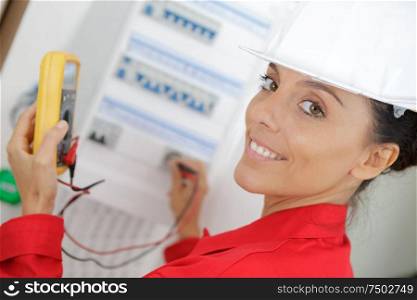 female electrician using multi meter on circuit breaker box