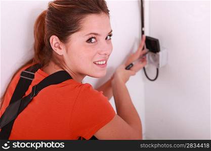 Female electrician wiring a wall socket
