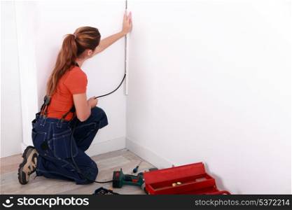 Female electrician wiring a white room