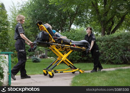 Female emergency medical team transporting senior patient on stretcher