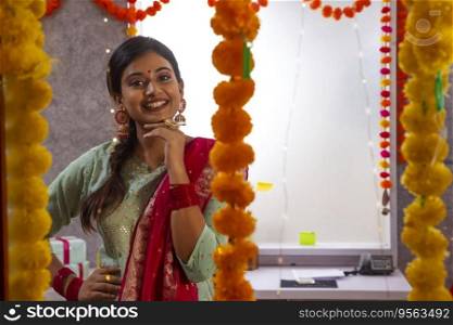 Female employee in traditional outfit gesturing in office during Diwali celebration