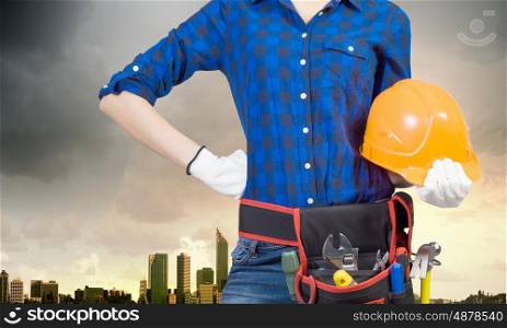Female engineer. Bottom view of woman engineer with tool belt on waist