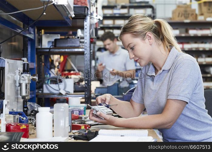 Female Engineer In Factory Measuring Component At Work Bench Using Micrometer