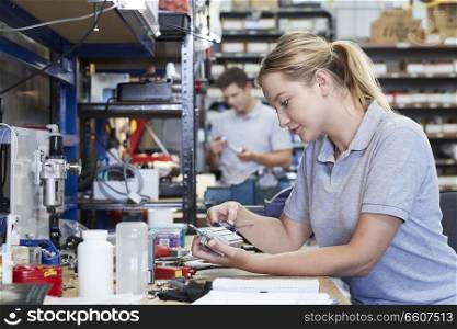 Female Engineer In Factory Measuring Component At Work Bench Using Micrometer