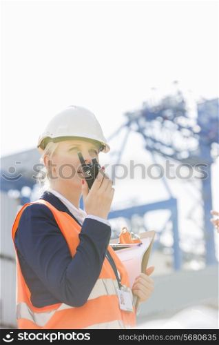 Female engineer using walkie-talkie in shipping yard