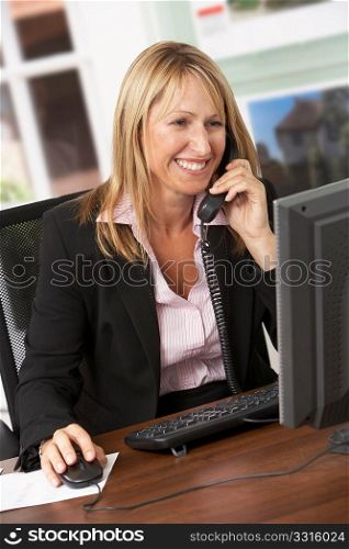 Female Estate Agent Talking On Phone At Desk