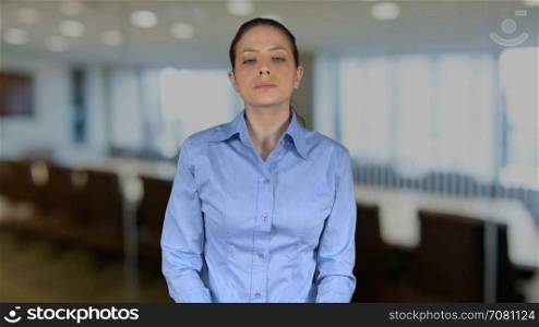 Female executive smiles with hands on hips in an office