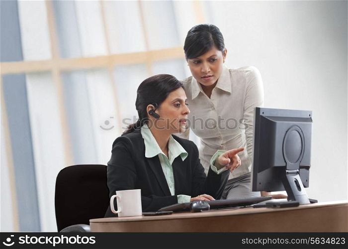 Female executives discussing while looking at computer