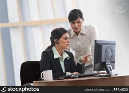 Female executives discussing while looking at computer