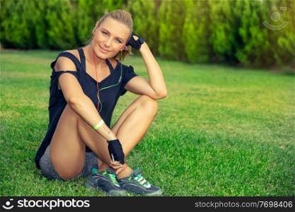 Female exercising outdoors, pretty blond woman relaxing after a good workout, listening music and meditating, sportive active lifestyle, wellbeing and healthy life of a young people