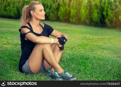 Female exercising outdoors, pretty blond woman relaxing after a good workout, listening music and meditating, sportive active lifestyle, wellbeing and healthy life of a young people