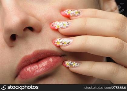 Female face close up and nail art. Figure of camomiles on nails
