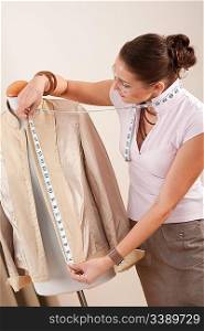 Female fashion designer taking measurement of jacket at studio