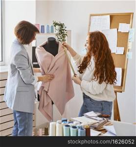 female fashion designers working atelier checking garment dress form