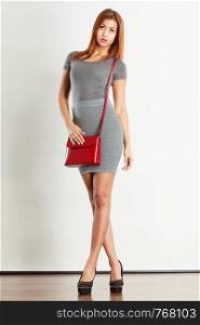 Female fashion. Girl mixed race in full length wearing fashionable gray outfit high heels shoes with red leather bag handbag. Studio shot. Mulatto girl gray wear with red handbag