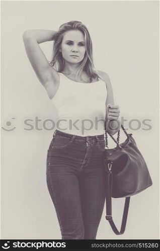 Female fashion - urban style. Young attractive trendy woman model posing outdoor with black bag in hand.. Trendy urban girl outdoors