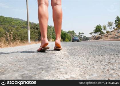 female feet are standing on country road