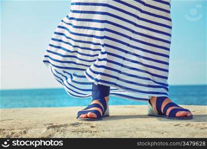 female feet in billowing dress against the background of the ocean