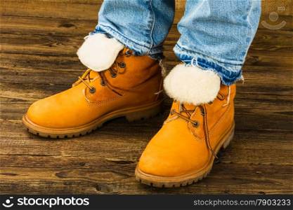 female feet in winter boots and jeans on wooden background