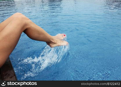 Female feet making splashes. Female feet in the pool making splashes