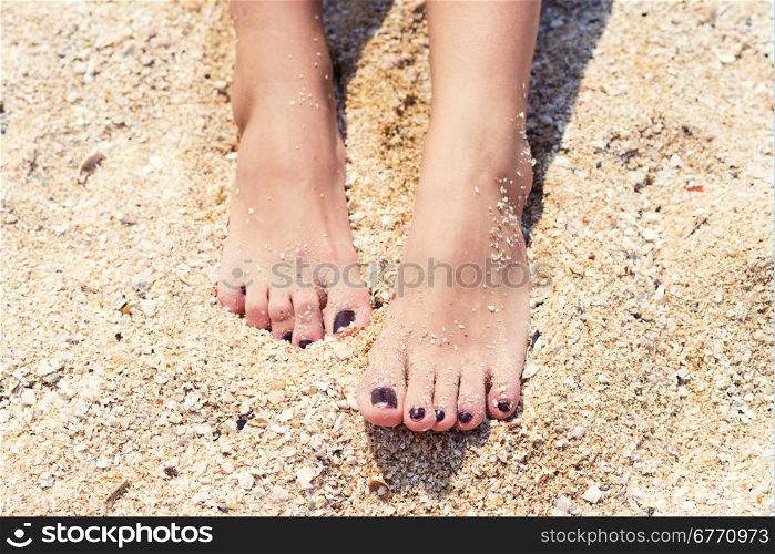 female feet with pedicure in beach sand