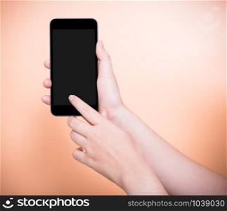 Female finger touch smartphone plus blank black screen on orange color background