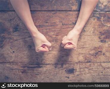Female fists clenched on a wooden table in anger