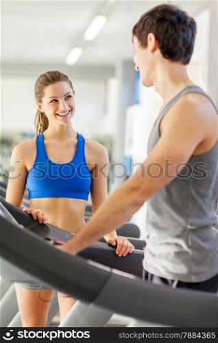 Female fitness instructor smiling towards young man on a treadmill