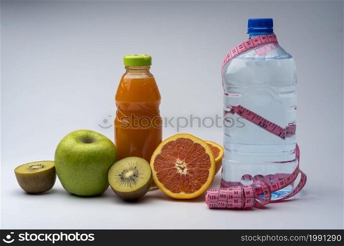 Female fitness still life. Healthy food, fruit, juice and water on grey background. Fitness, sports and healthy lifestyle concept.. Female fitness still life. Healthy food, fruit, juice and water on grey background.