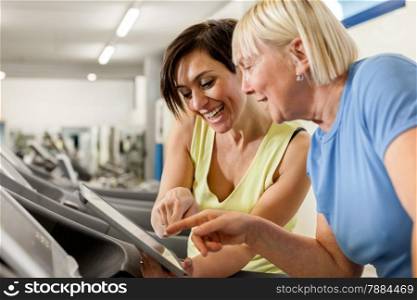Female fitness trainer is discussing program with woman on a treadmill
