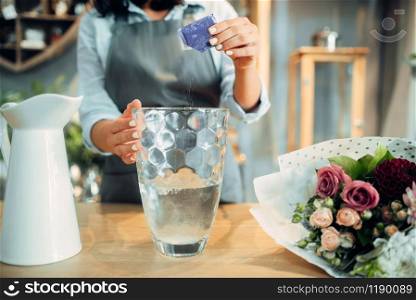 Female florist adds fertilizer to the water for flowers. Floristry service, floristic business, floral shop